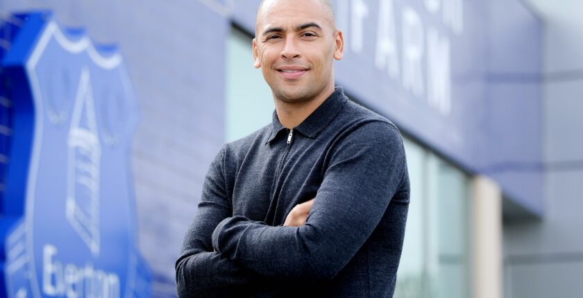 James Vaughan standing in front of Everton Logo
